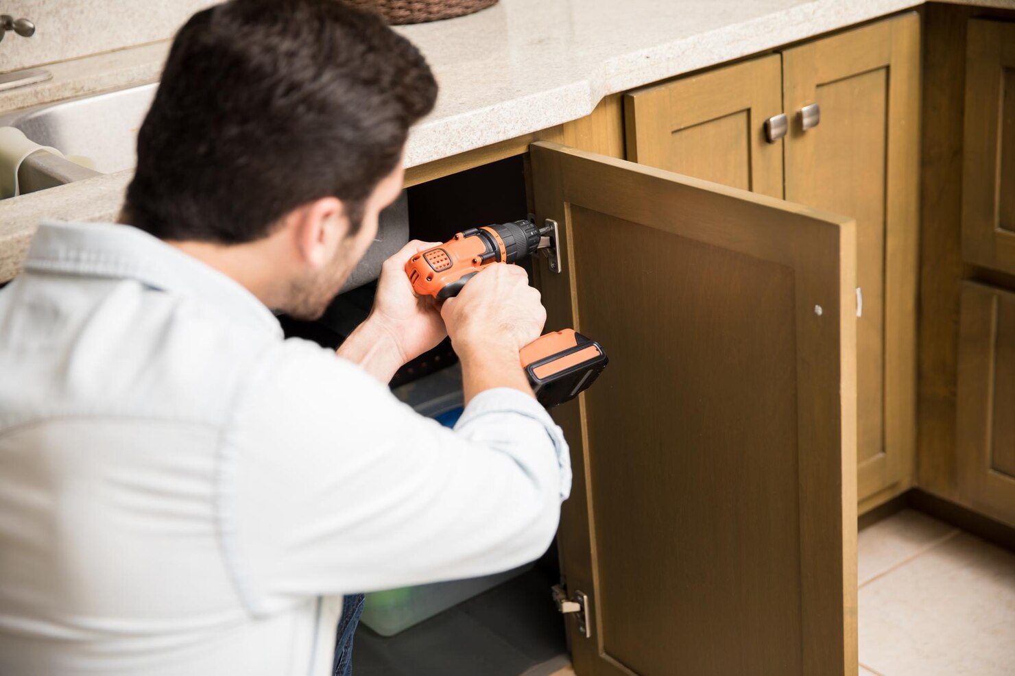 point-view-young-handyman-using-power-drill-fix-door-kitchen-cabinet_662251-2704
